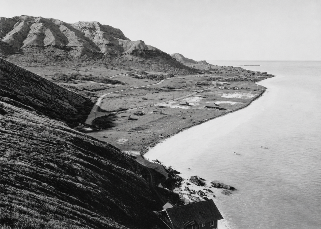 Historic black-and-white view of early Lanikai, Oahu, from the Waimanalo side, showing sparse homes, early roads, open coastal land, and the Koolau foothills.