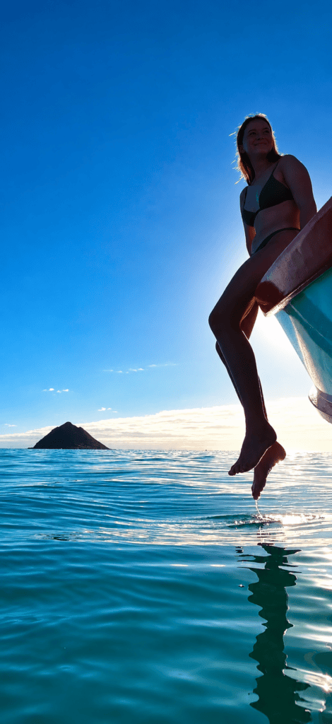 Rick Maxey’s daughter seated aboard the Homer Albert off Lanikai, with turquoise water and a Mokulua island in the background