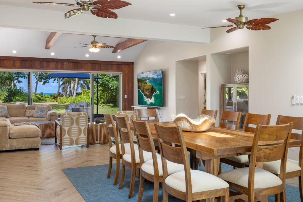 Dining table for twelve beside the living room and ocean-facing sliders at Kailuana Beachfront Estate