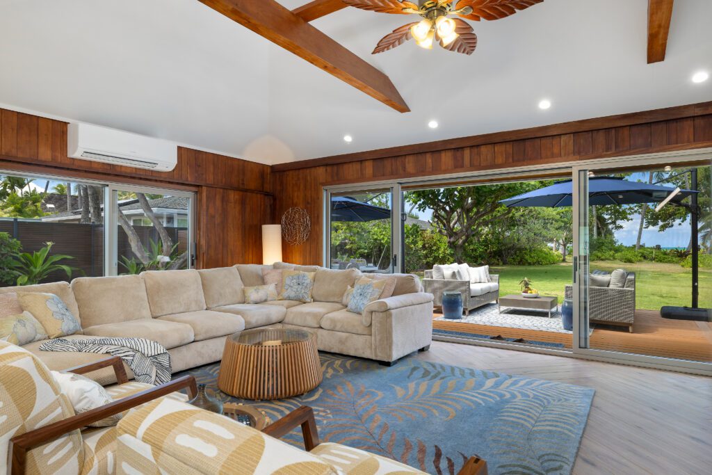 Living room with sectional sofa, wood-beam ceiling and sliding doors to the lanai at Kailuana Beachfront Estate