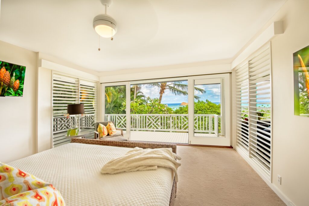 Primary bedroom opening to the ocean-view lanai at Kehaulani Ridge