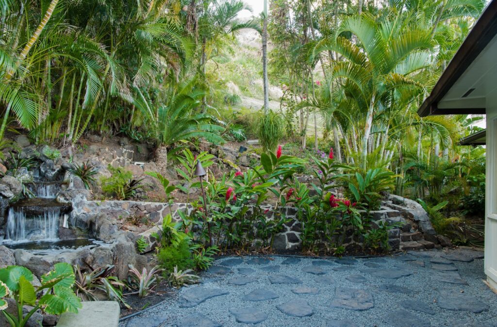 Waterfall, pond and flagstone path in the tropical garden at Kehaulani Ridge
