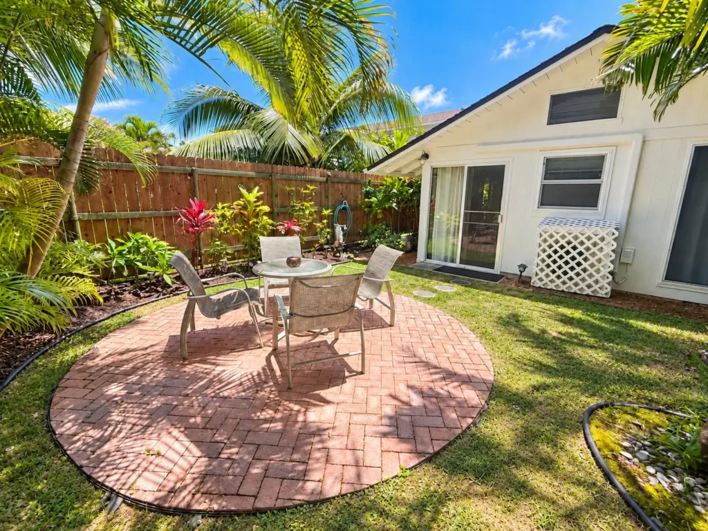 Circular brick garden patio with glass-top table at Lanikai Garden Studio