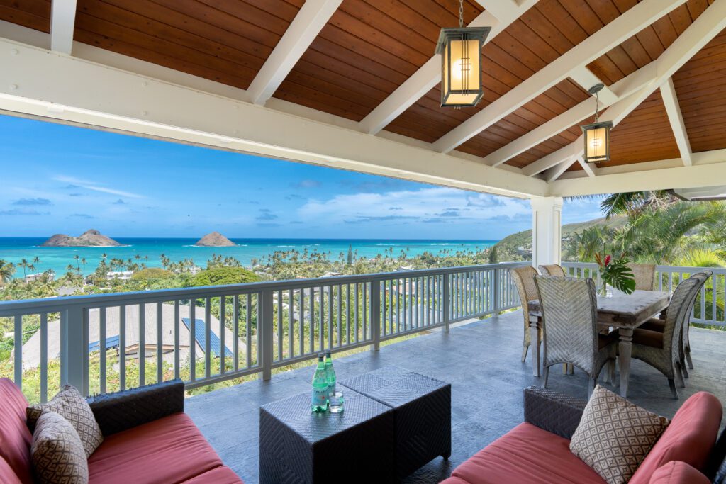 Covered lanai with red lounge seating overlooking Lanikai and the Mokulua Islands at Makani Moana