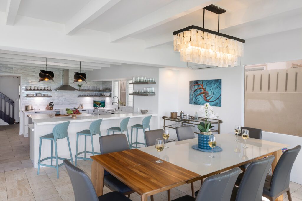 Dining table and kitchen beneath a crystal chandelier at Moku Nui