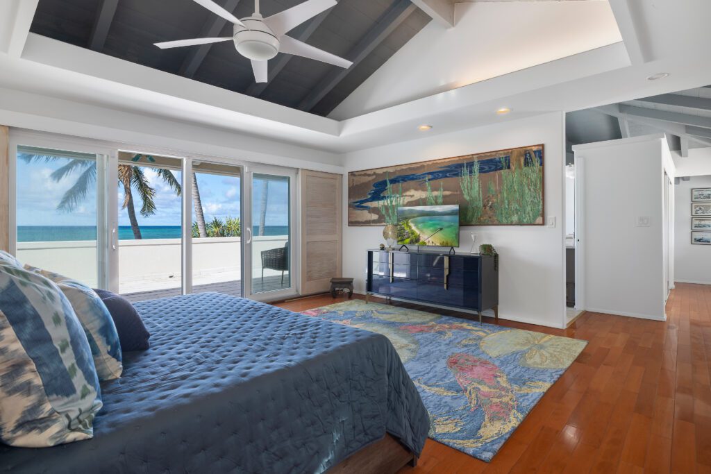 Upstairs primary suite with king bed and vaulted ceiling at Moku Nui