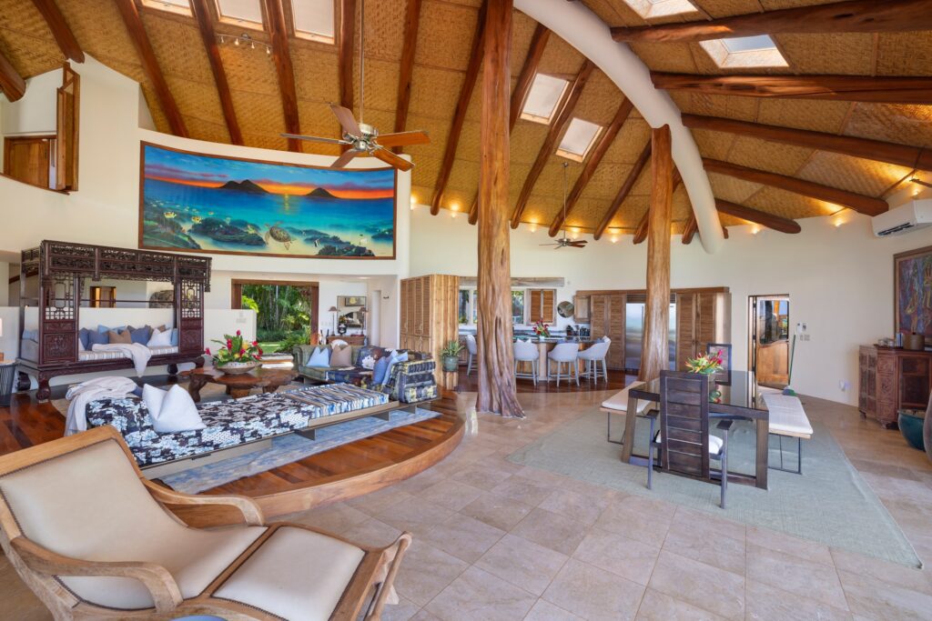 Main house great room with ʻōhiʻa log columns and woven grass-cloth ceilings at Paul Mitchell Estate