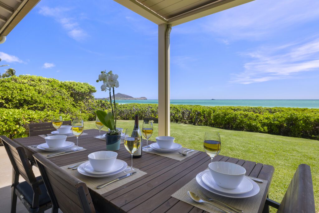 Lanai dining table set with ocean and island views at Pueohala