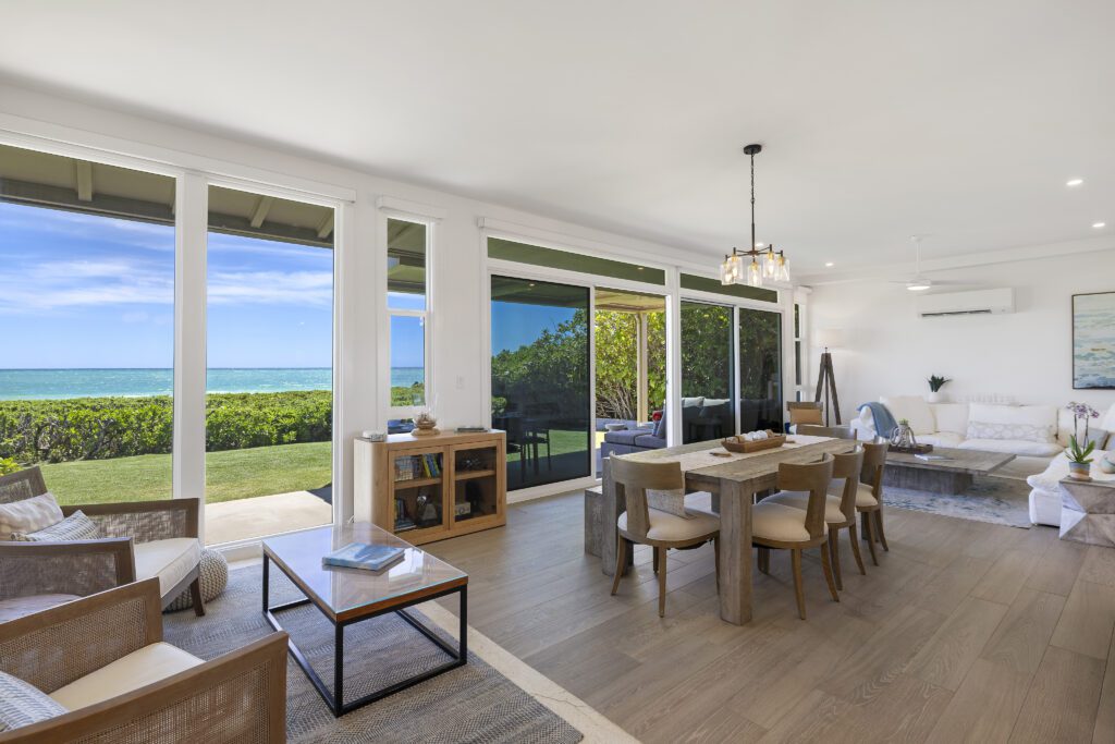 Open living and dining room with walls of glass facing the ocean at Pueohala